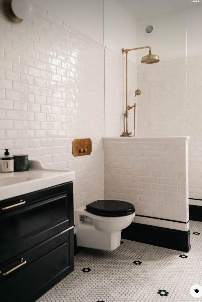 A modern bathroom showcasing a black and white tile design, including a white toilet in the corner.
