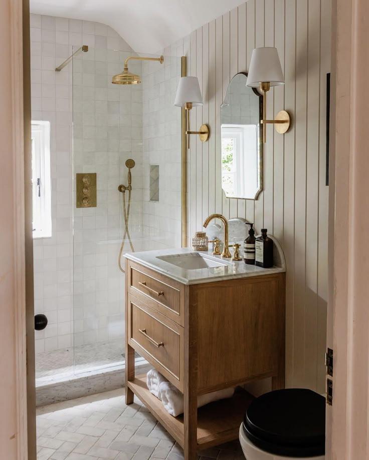 A stylish bathroom interior with a wooden vanity and a glass shower, creating an inviting atmosphere.