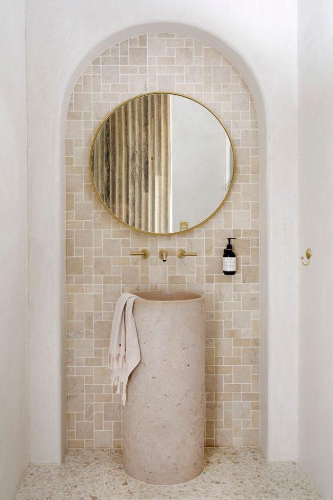 A modern bathroom interior with a round mirror and a sink, highlighting a fresh and uncluttered aesthetic.