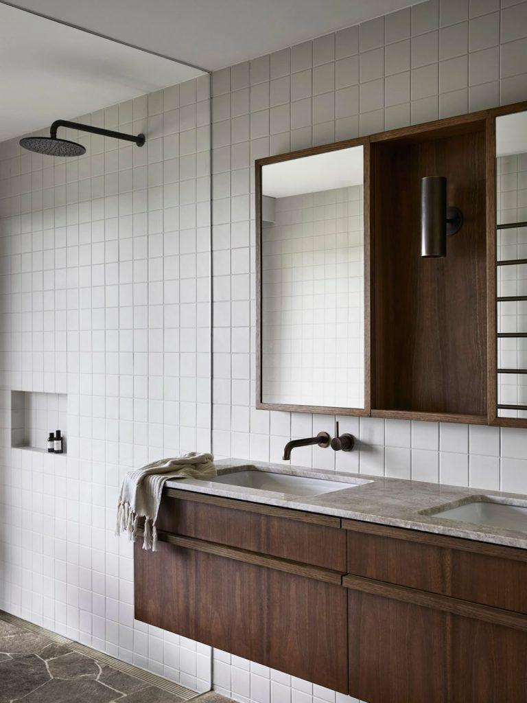 A cozy bathroom with a wooden vanity and a sleek shower, highlighting a blend of functionality and style.