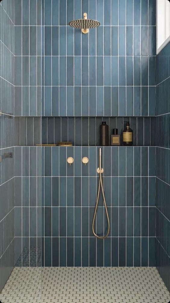 A stylish shower with blue tiles, complete with a shower head and a mounted shower rod.