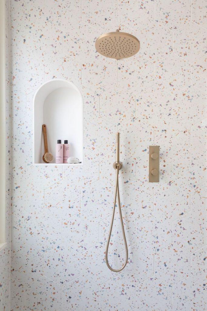 A bathroom scene featuring a shower with a shower head and a sink, showcasing modern fixtures and clean design.
