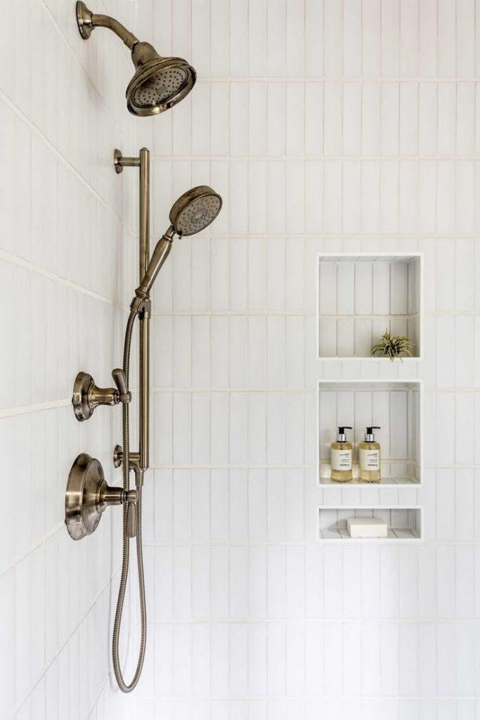 A modern shower featuring a sleek shower head mounted on the wall, with water droplets visible.
