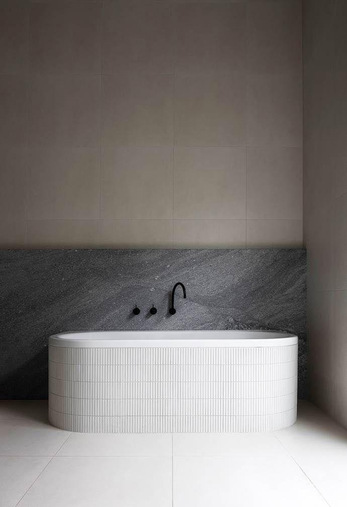 A spacious bathroom showcasing a large bathtub alongside a stunning marble wall.