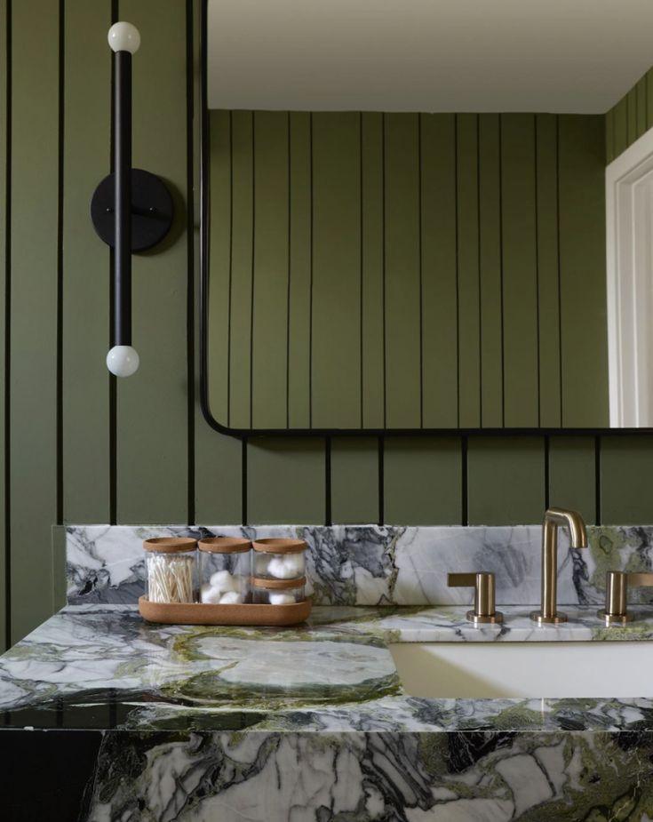 A bathroom featuring green walls and elegant marble countertops.