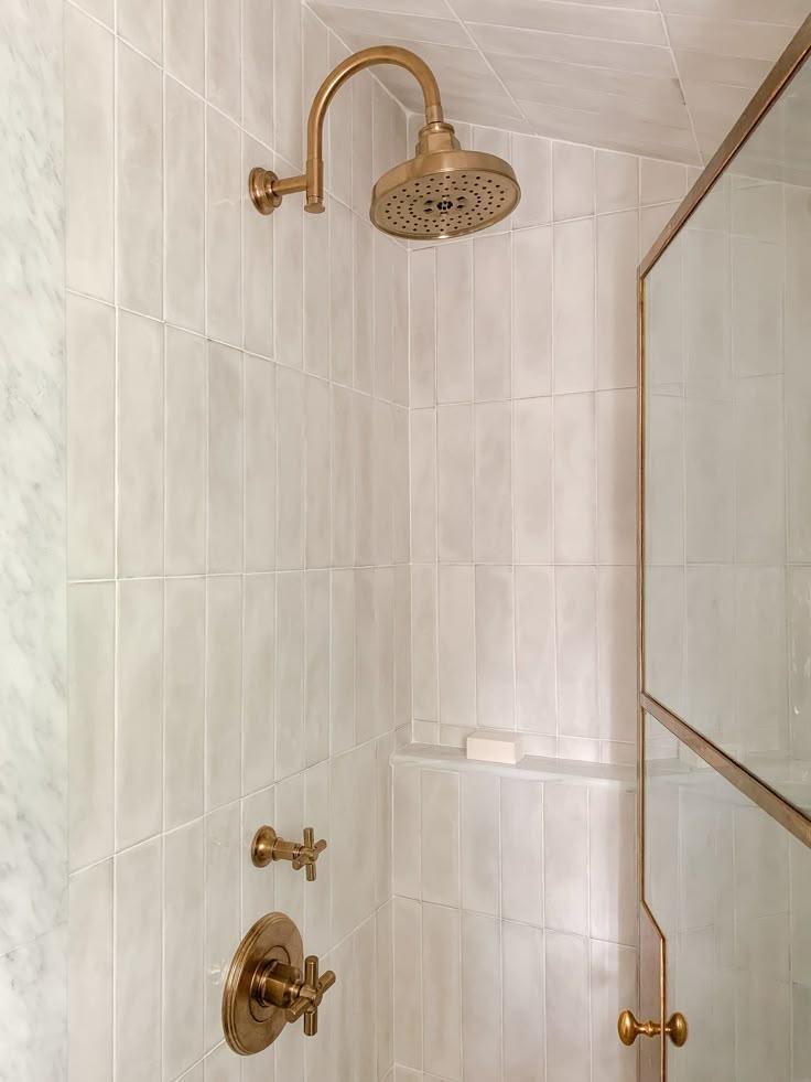 A bathroom featuring a shower head and elegant brass fixtures, showcasing a modern and stylish design.