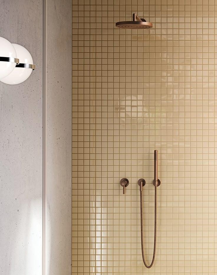 A clean bathroom featuring a shower and a sink, with neutral-colored tiles and modern fixtures.