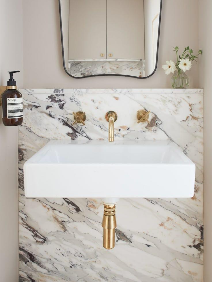 An elegant bathroom with a marble sink and polished gold fixtures, highlighting a modern design.