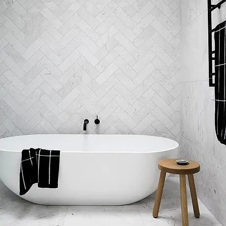 Elegant bathroom with a white bathtub and a striking black and white tile design on the walls and floor.