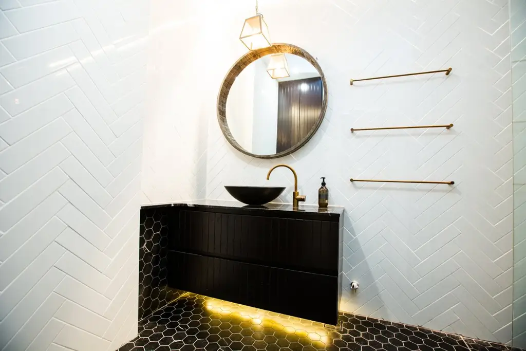 Modern bathroom with a striking black and white tile pattern and a round mirror above the sink area.