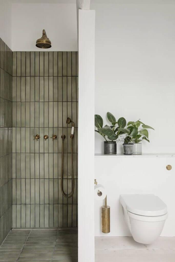 A well-designed bathroom with a shower, toilet, and an eye-catching green wall.