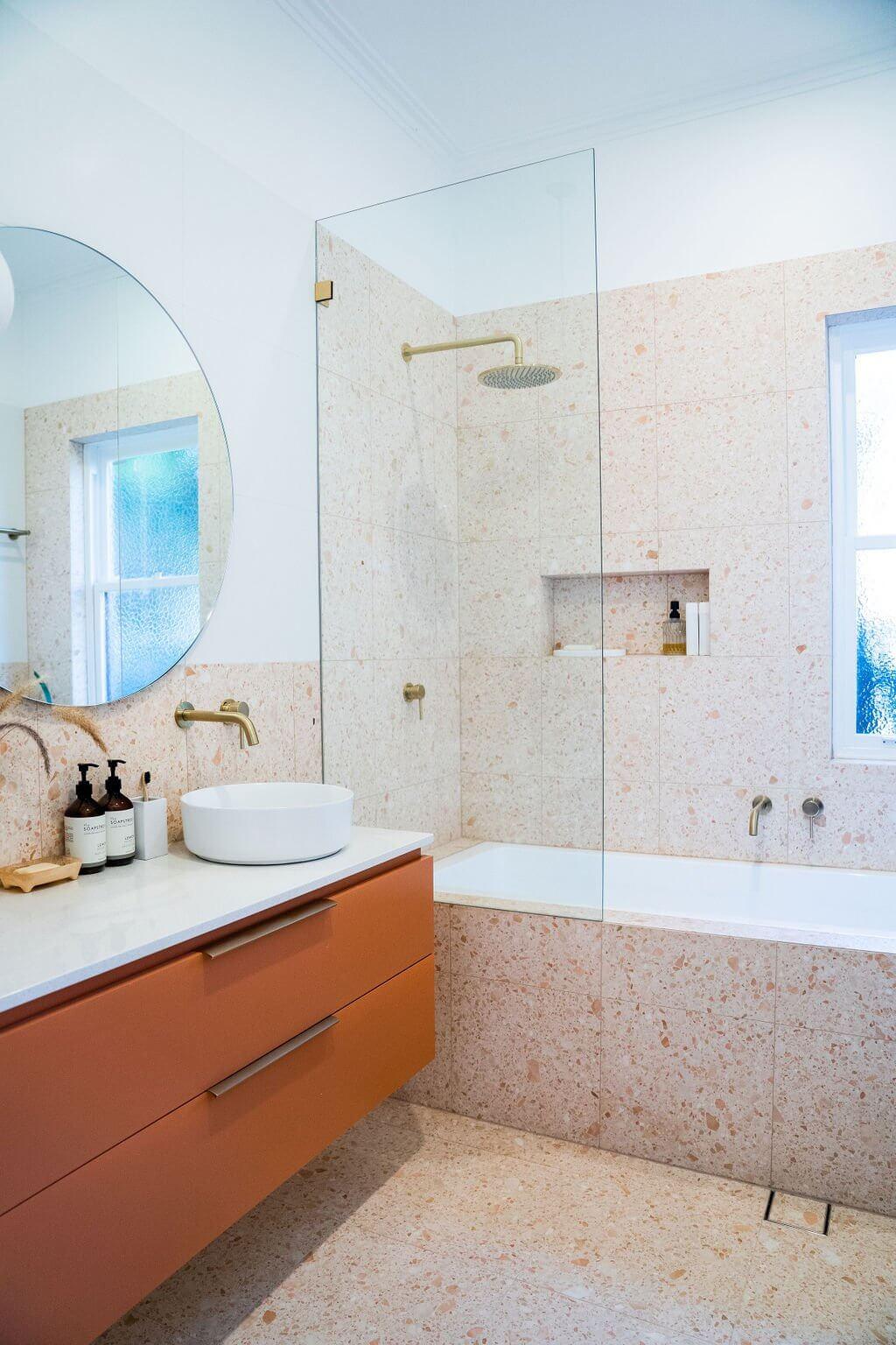 Ensuite shower area with round mirror, terracotta vanity, terrazzo tile and brass tapware