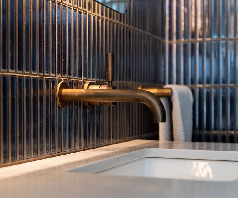 A stylish bathroom sink with a brass faucet and a rectangular mirror reflecting the space.