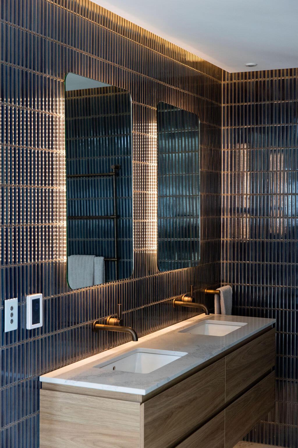 Modern bathroom interior with striking blue tile walls and rich wooden cabinets, emphasizing a sophisticated design.