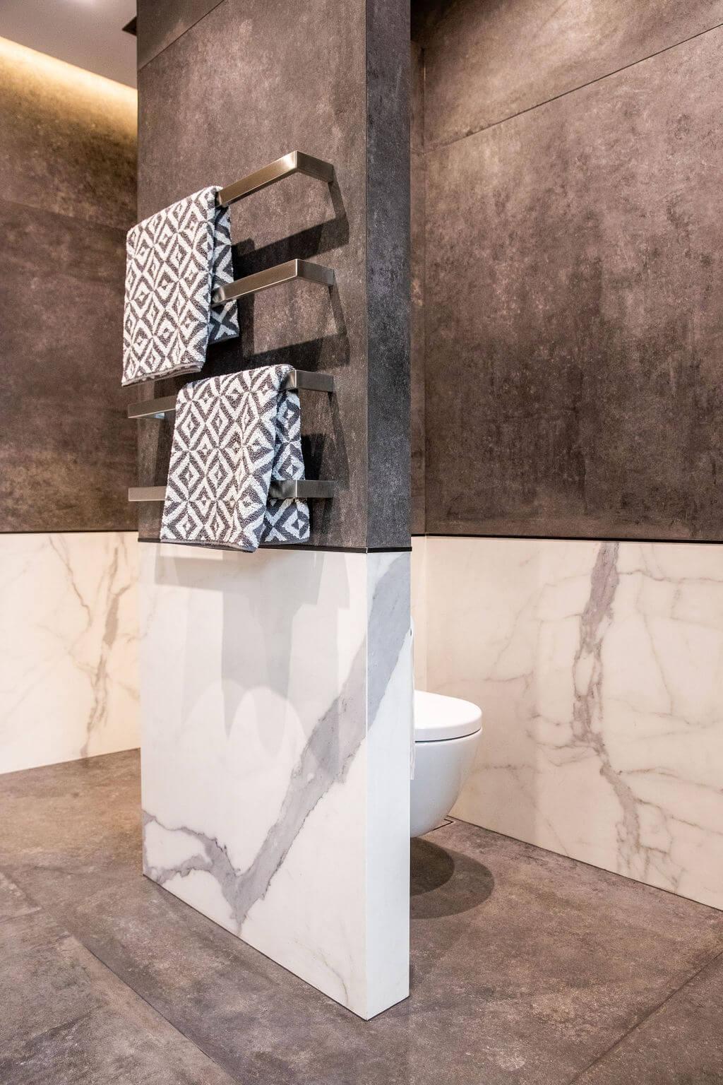 A bathroom featuring elegant marble walls and a white toilet, showcasing a modern and clean design.