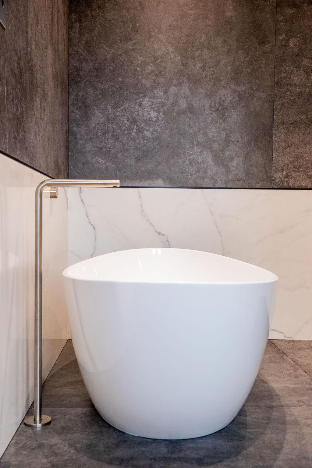 A sleek modern bathroom featuring a spacious white bathtub as the focal point.