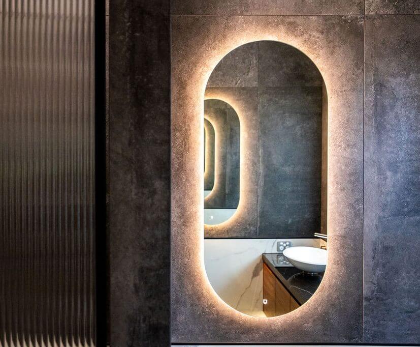 A bathroom featuring a circular mirror above a modern sink, with neutral-colored walls and minimal decor.