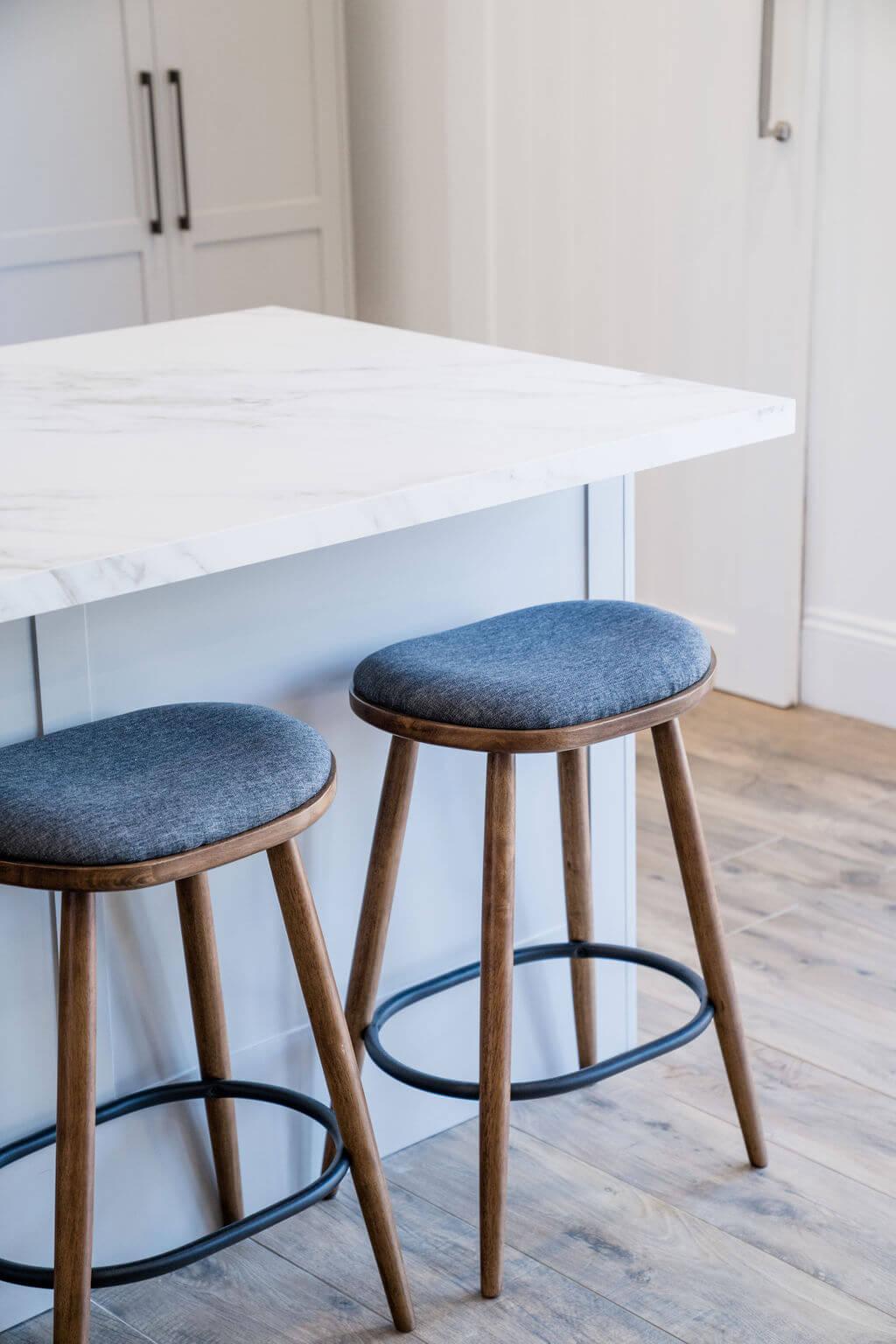 Two wooden stools positioned on a sleek white countertop.