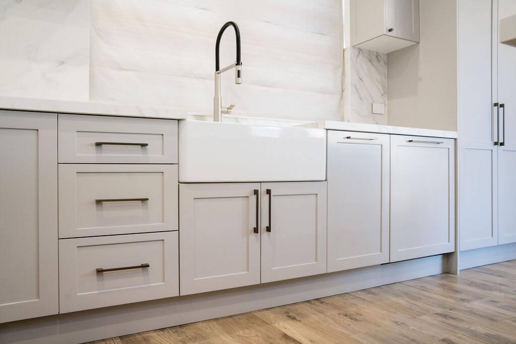 A modern kitchen featuring white cabinets and a stainless steel sink.