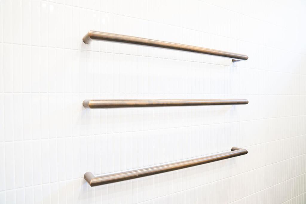 A bathroom featuring three metal grab bars mounted on the wall for support and accessibility.