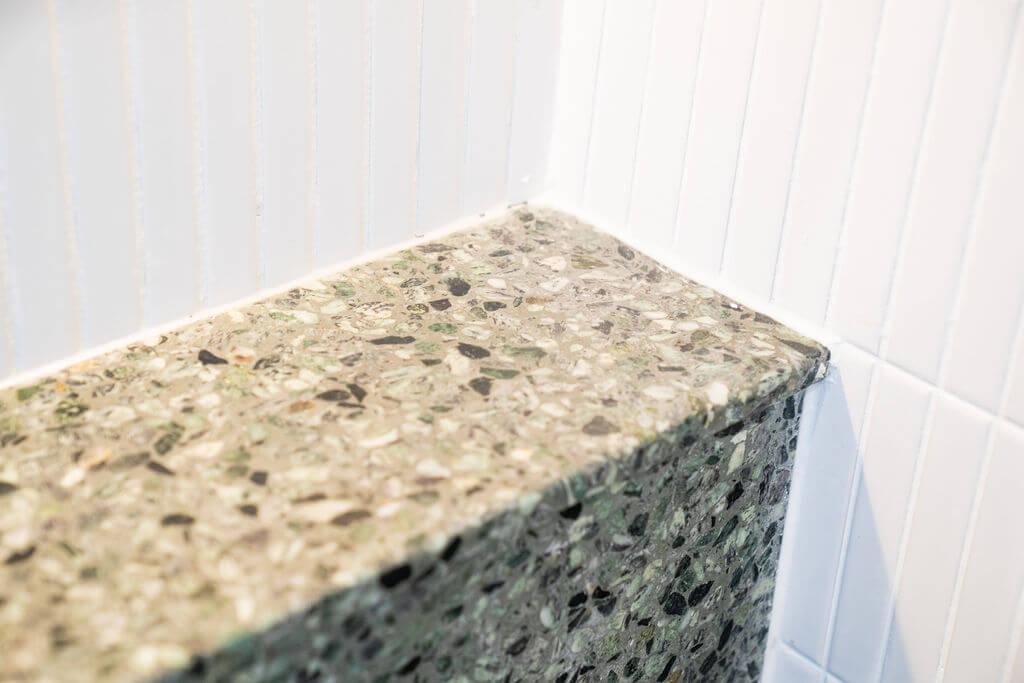 Detailed view of a white tiled wall alongside a sleek green counter, highlighting contemporary decor elements.