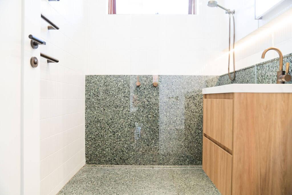 A stylish bathroom with green tiled walls and elegant wood cabinets, offering a modern yet warm atmosphere.