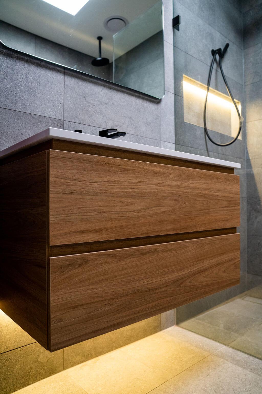 A bathroom featuring a wooden vanity and a modern shower, showcasing a clean and stylish design.