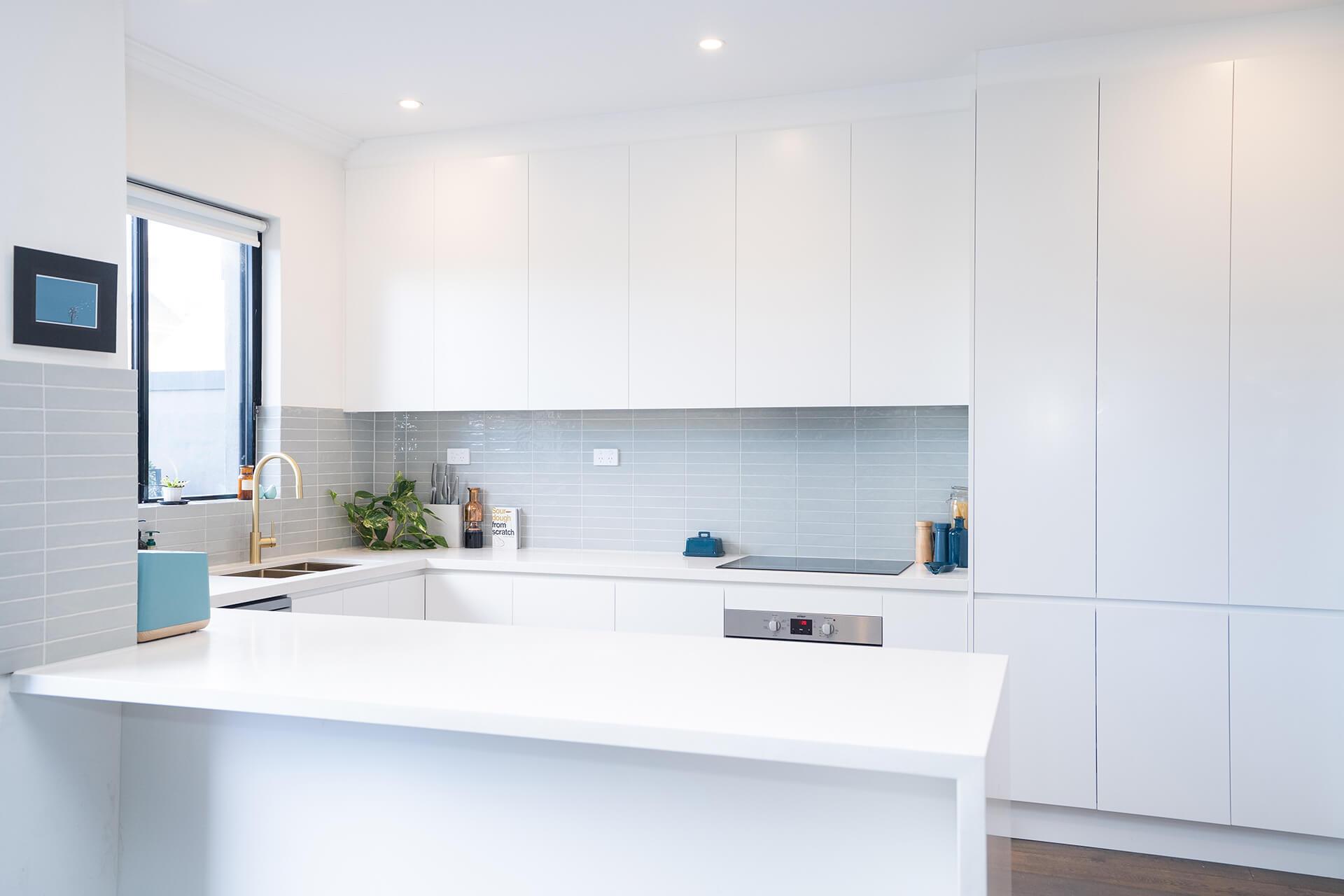 A bright, clean white kitchen featuring a sink and spacious counter area.