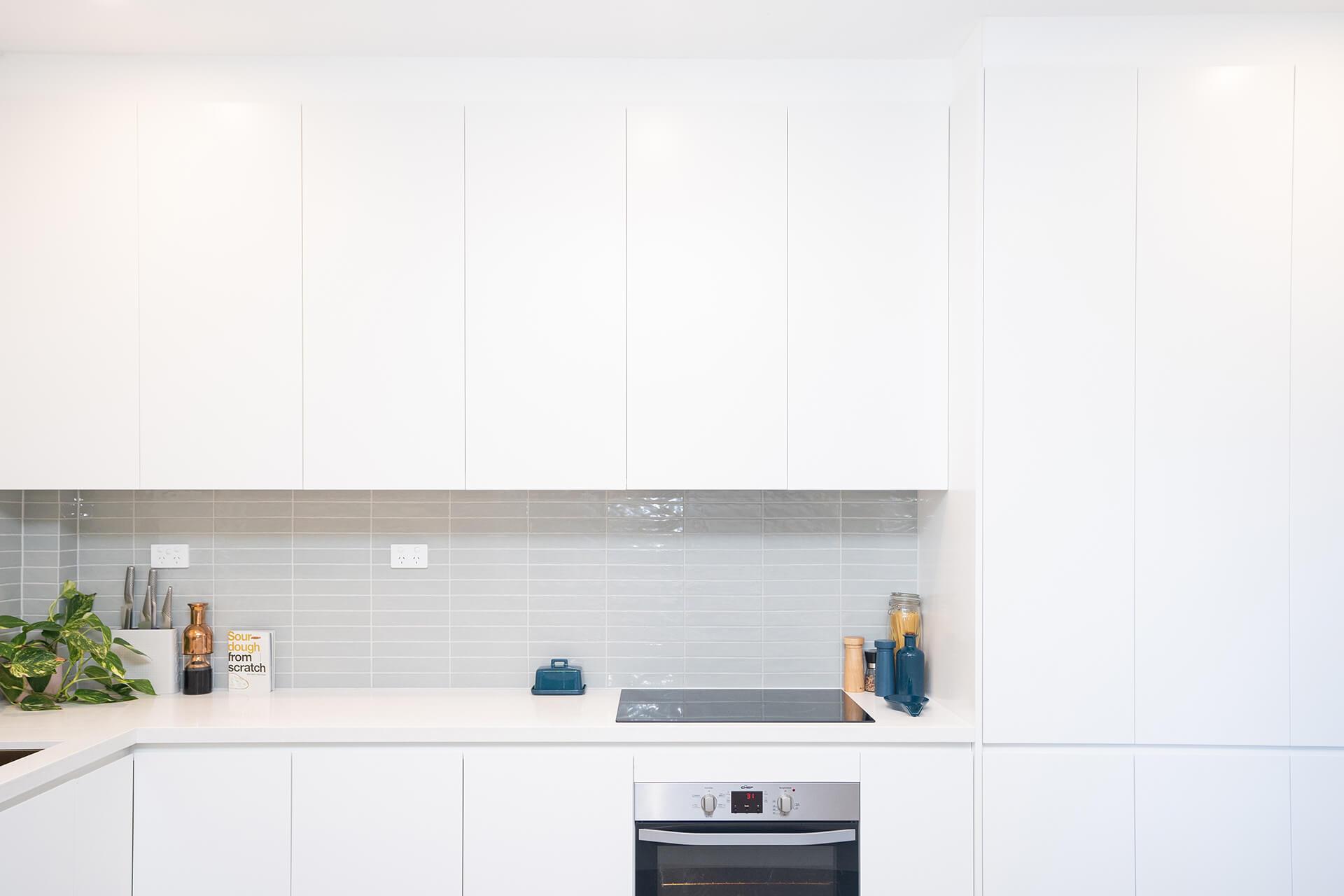 A bright white kitchen featuring a sink and an oven, showcasing a clean and modern design.