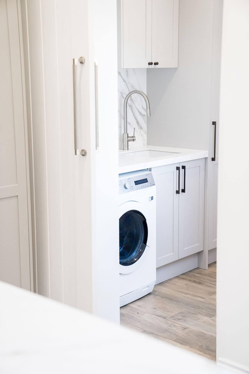 A white washer and dryer set in a compact laundry room with light-colored walls and minimal decor.