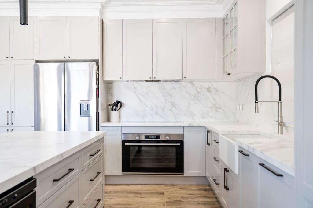 A spacious white kitchen with beautiful marble countertops, emphasizing a fresh and airy atmosphere.