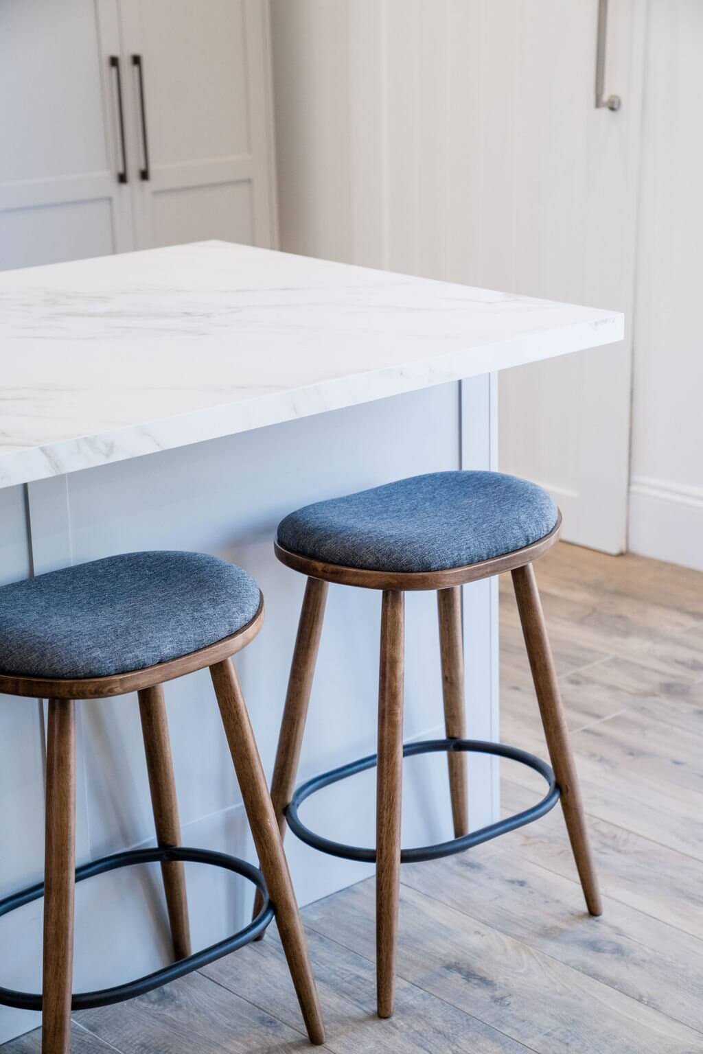 Two modern stools positioned at a marble countertop in a stylish kitchen setting.