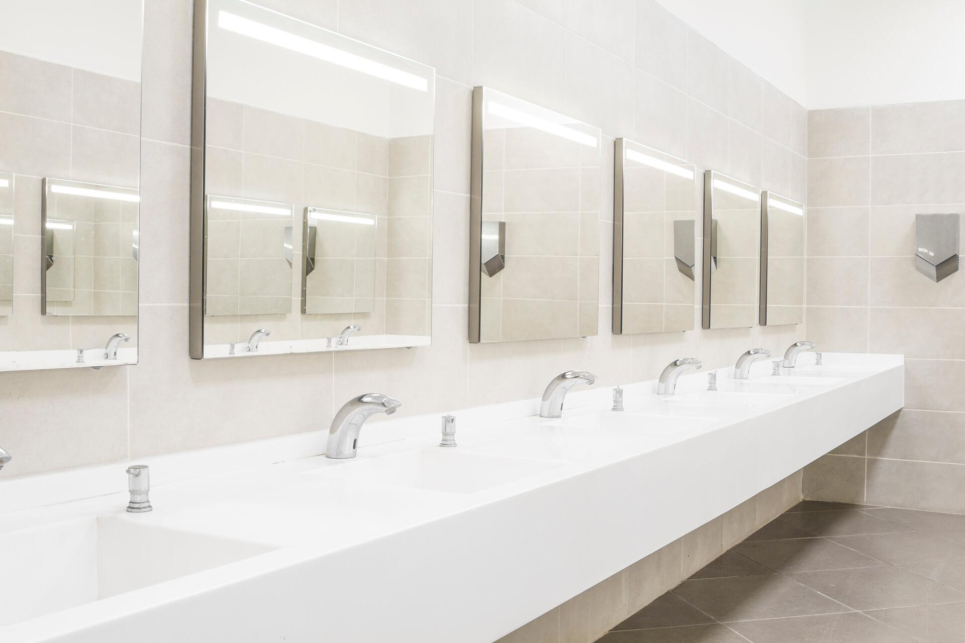 Sydney commercial bathroom with long white countertop basins, modern chrome taps, and multiple mirrors.