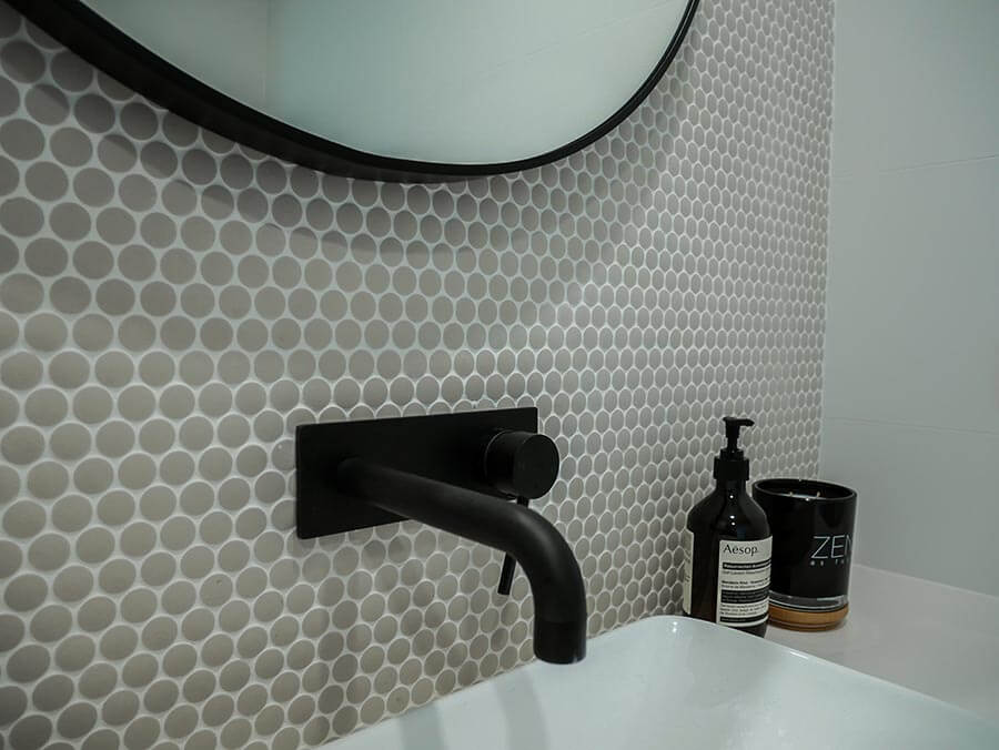 A clean bathroom showcasing a white sink paired with a contemporary black mirror.