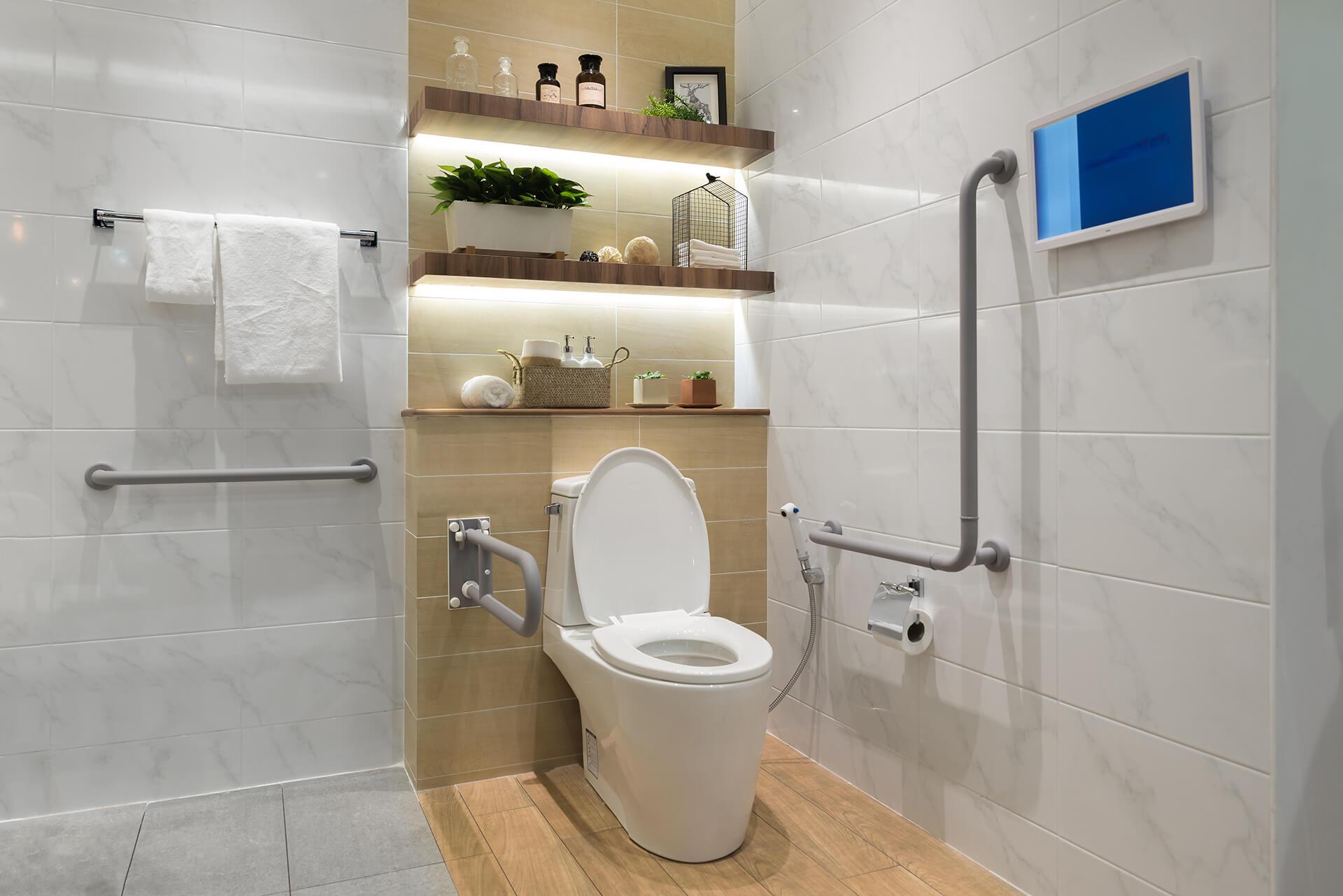 A clean bathroom with a white toilet, sink, and glass-enclosed shower, set against light-colored walls.