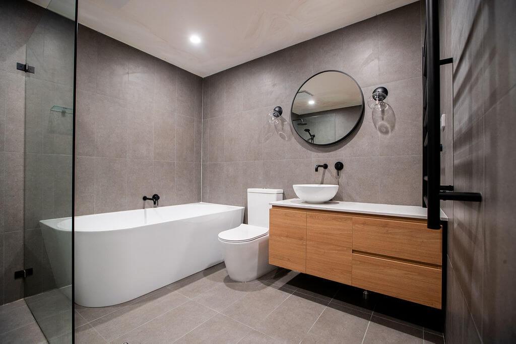 Contemporary bathroom with freestanding bathtub, wall-hung vanity, round mirror, and matte black fixtures.
