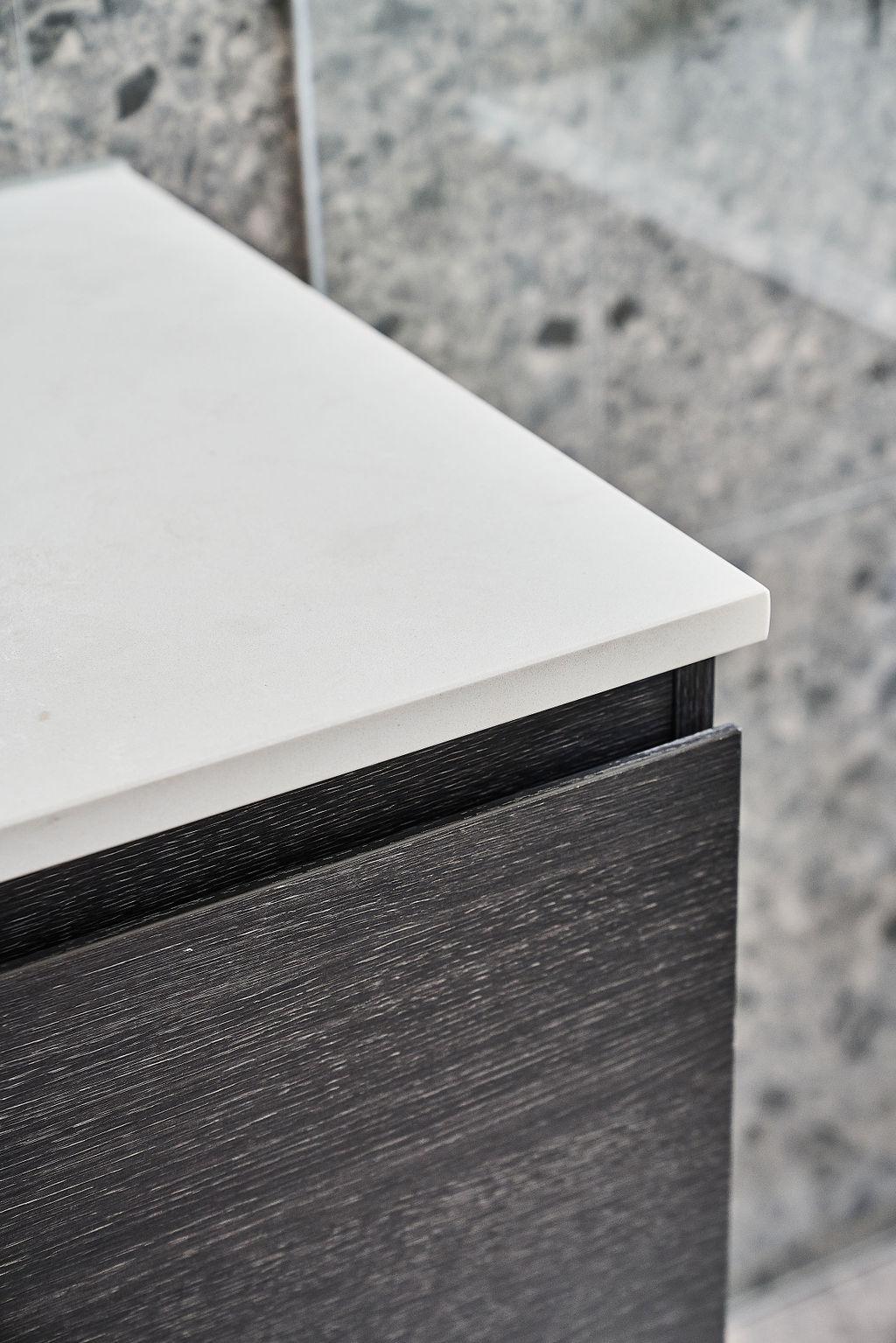 Close-up of white stone benchtop corner against dark timber vanity
