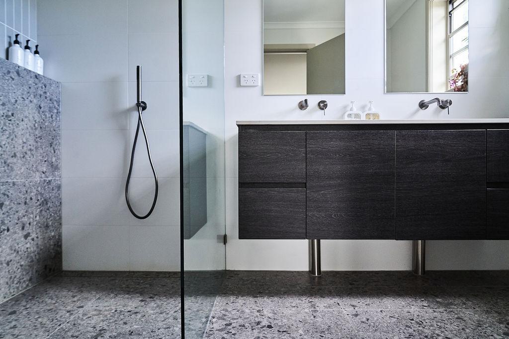 Second bathroom vanity and mirror with dark cabinet and glass shower screen