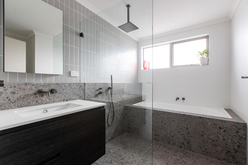 Walk-in shower with grey terrazzo look tile hob, glass screen and ceiling shower head