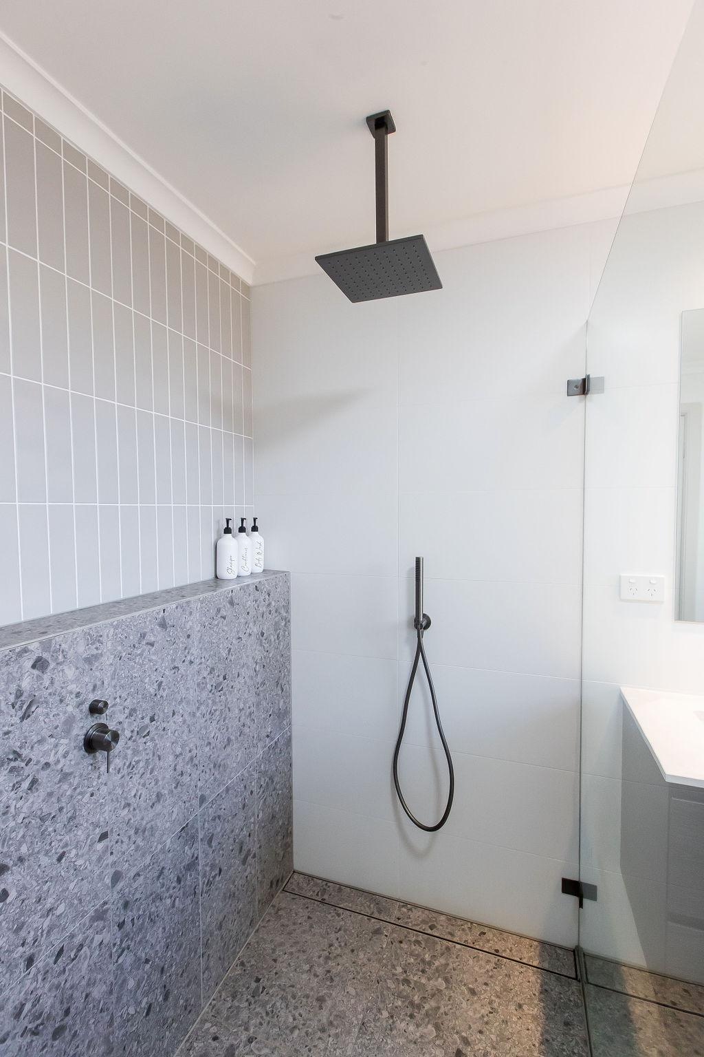 Second bathroom shower recess with terrazzo tile and ceiling shower head