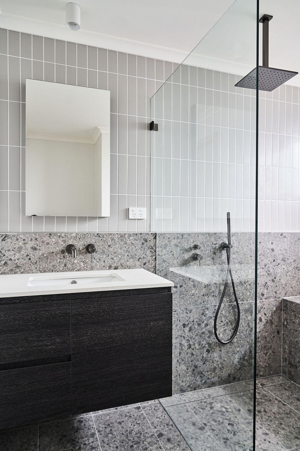 Second bathroom vanity and mirror with terrazzo splashback, glass shower screen visible