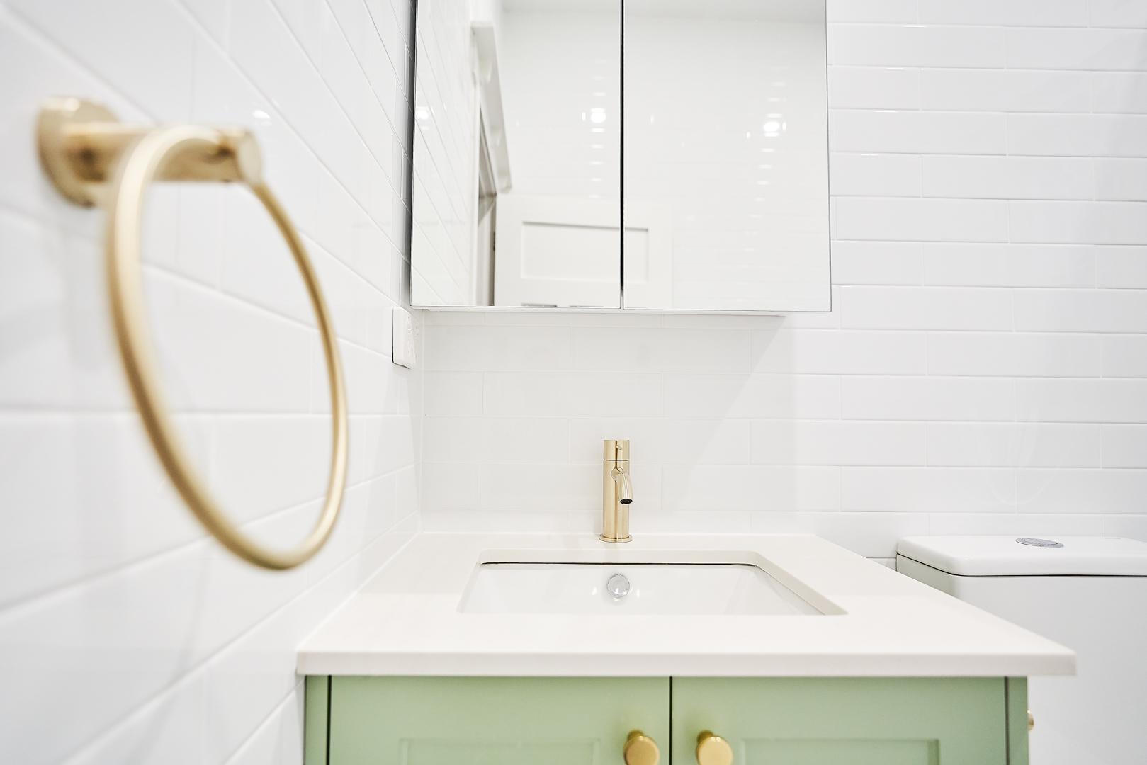 A bathroom scene with a green cabinet complemented by white tile surfaces.