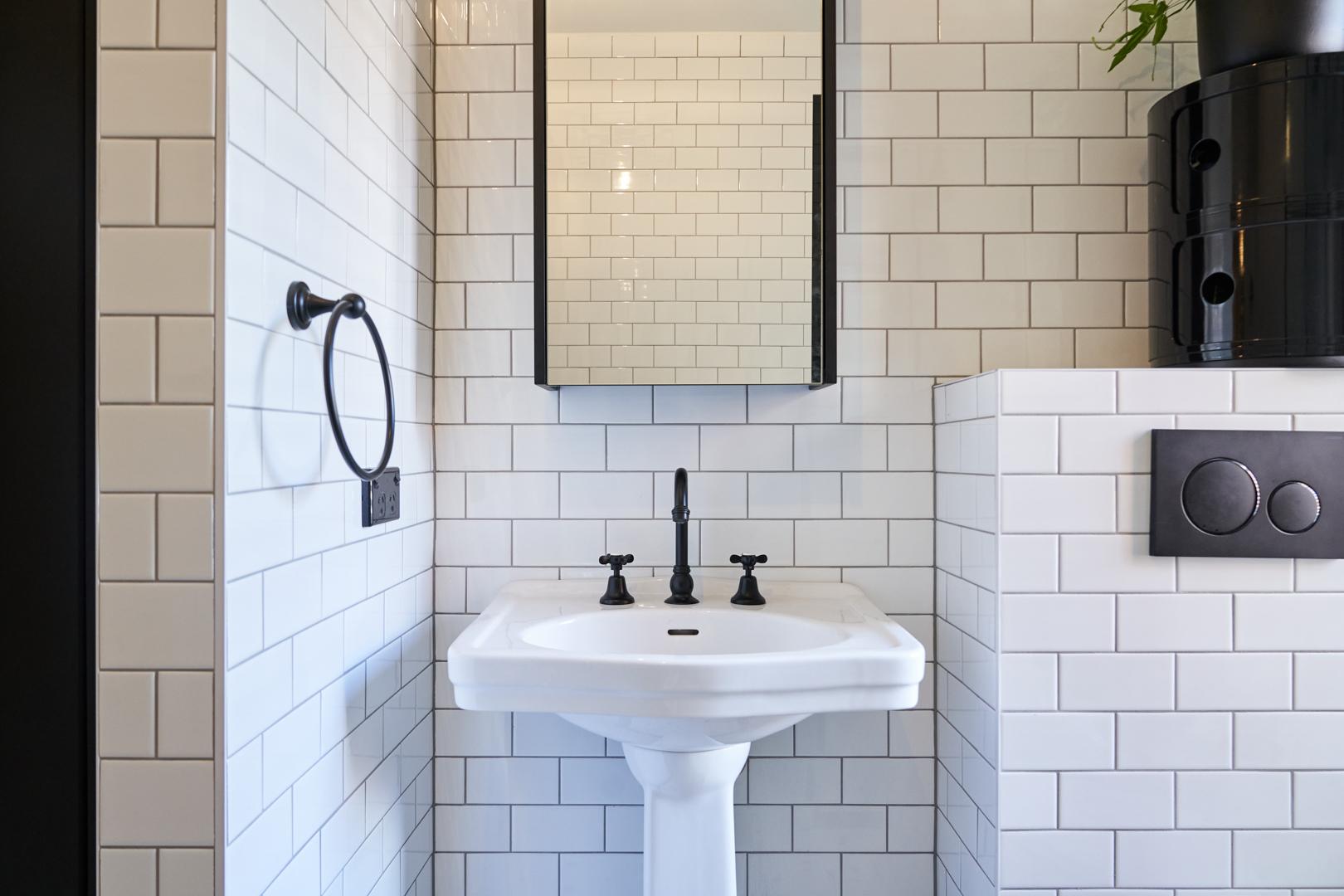 A modern bathroom featuring white subway tiles complemented by sleek black accents.