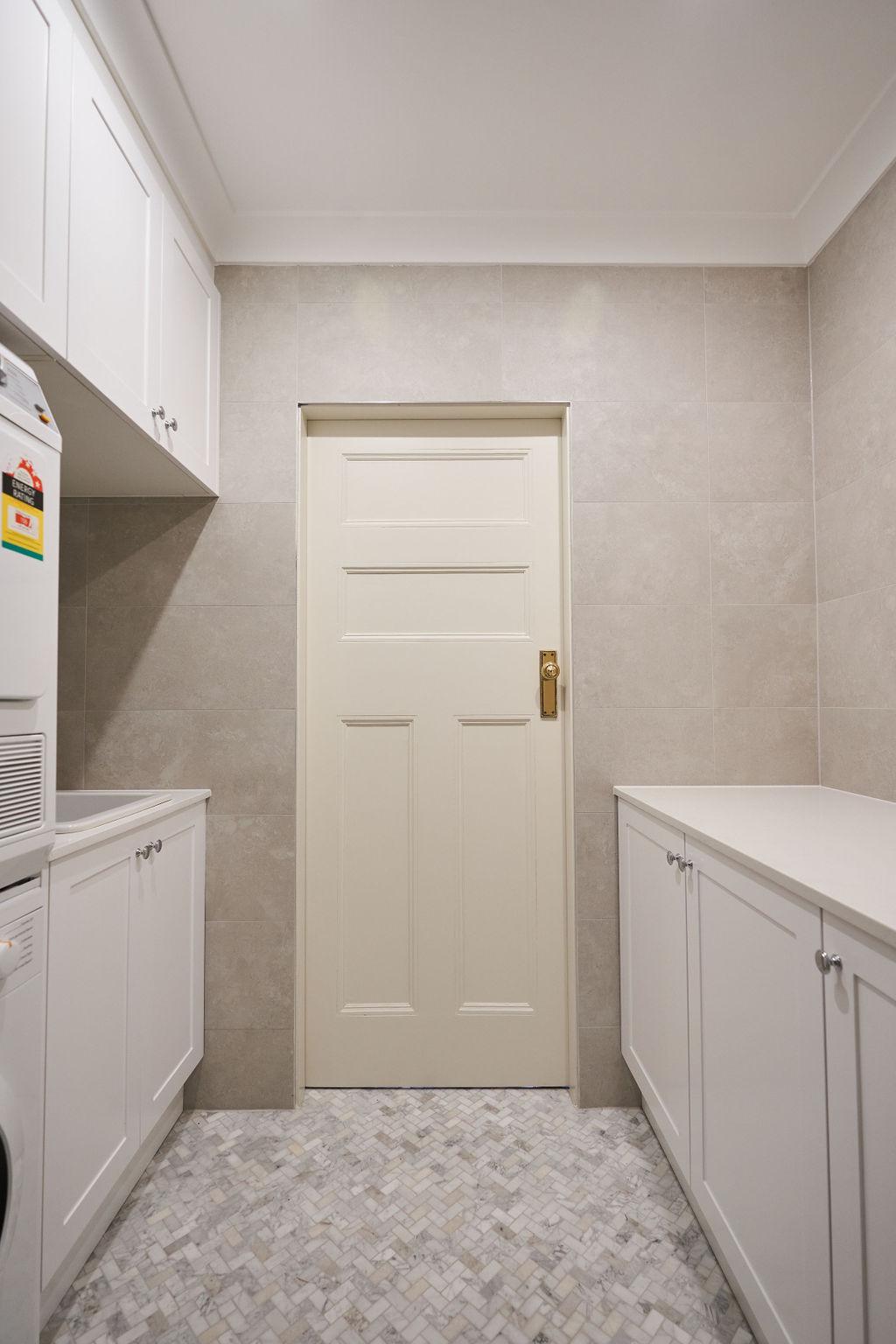 A bright white laundry room featuring a door and a washing machine against a clean, minimalist backdrop.