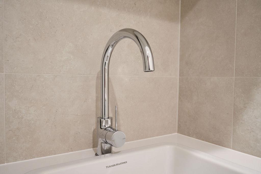 A stylish laundry showcasing a white sink paired with a modern faucet.