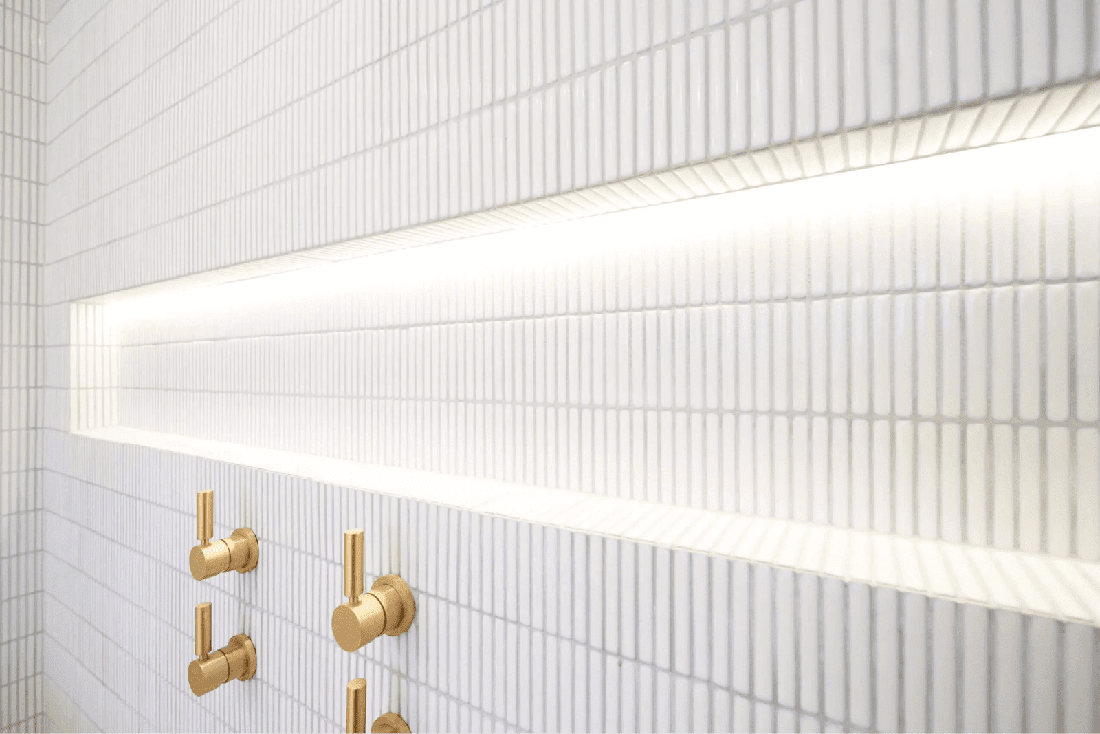A stylish bathroom with pristine white tiles complemented by sophisticated gold fixtures, enhancing its elegance.