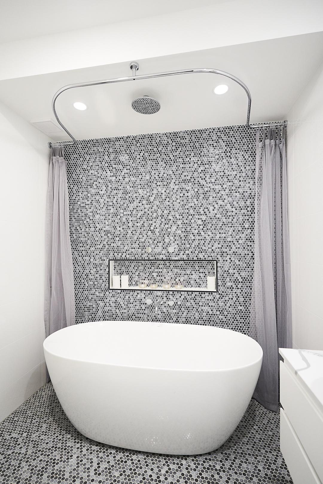 A white bathtub is displayed in a bathroom adorned with a decorative mosaic tile floor.