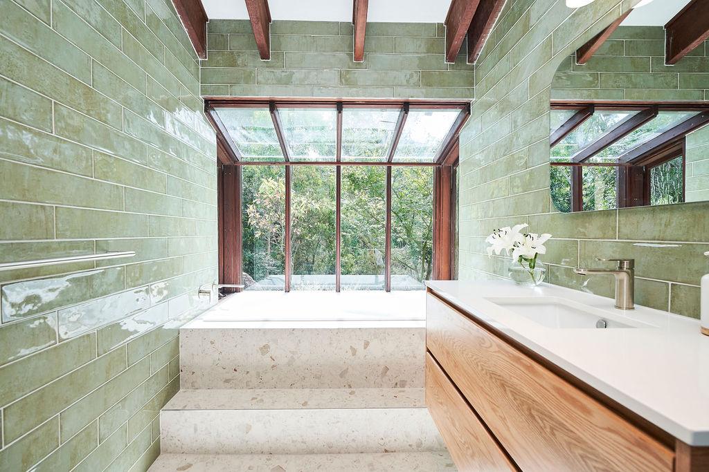 A bright bathroom featuring a large window and a stylish green tile floor.