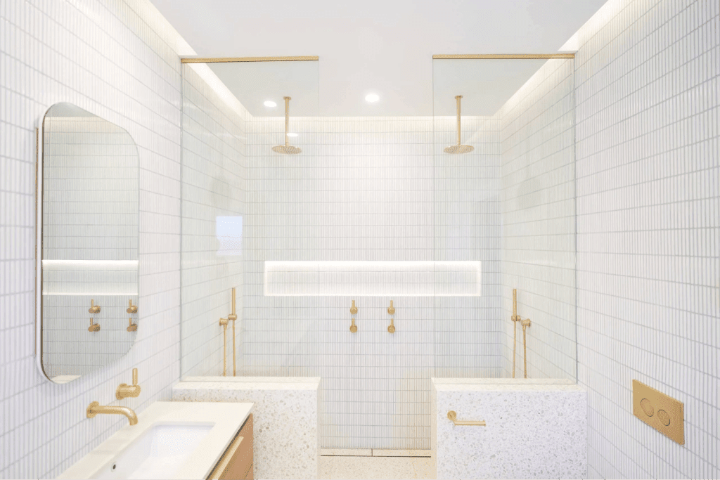 A modern bathroom featuring a glass shower enclosure and elegant gold fixtures.