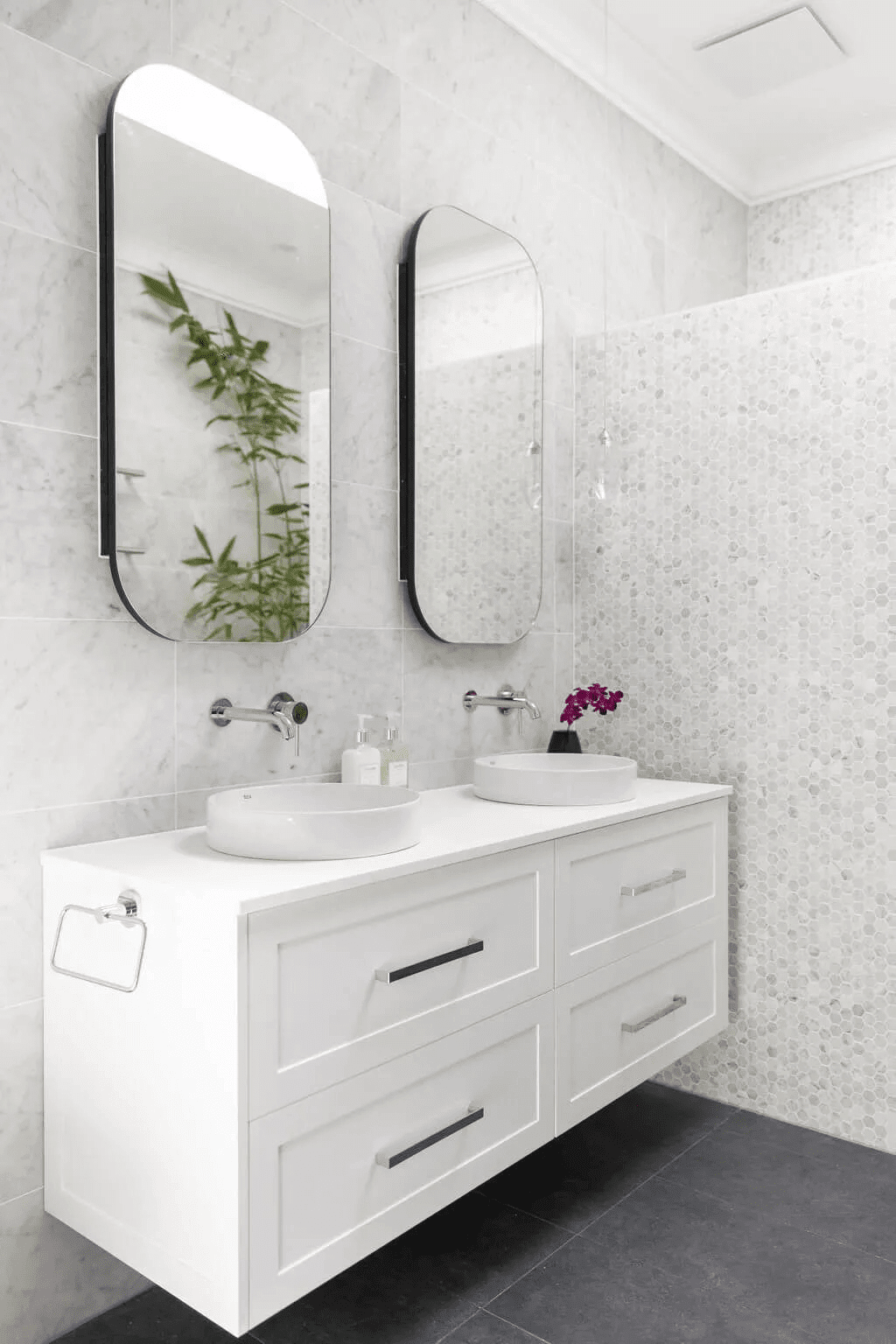 A sleek modern bathroom featuring a round mirror above a stylish black countertop.